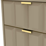 A close-up of a beige cabinet with geometric detailing and gold handles, suggesting a modern interior design element.