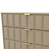 A beige geometric-patterned dresser with gold handles partially opens one drawer, revealing a reflection on a glossy surface below.