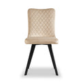 A beige, upholstered dining chair with quilted backrest and black angular legs stands against a white background.