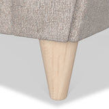 A wooden furniture leg supports a section of a couch with a textured gray fabric, set against a neutral background.