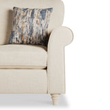 A beige armchair with a cushion featuring an abstract design with neutral and blue tones, positioned against a white background.