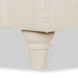 A furniture leg supports a beige upholstered object on a plain light background.