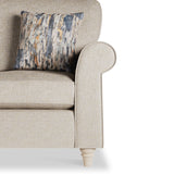 A beige textured armchair with a patterned cushion against a white background.