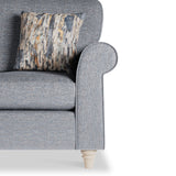 A gray fabric armchair with a patterned cushion rests against an isolated white background.