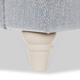 A wooden furniture leg supports a piece of light blue fabric on a white background.