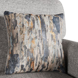 Patterned cushion resting on a gray textured couch, featuring abstract streaks in blue, gray, and orange hues.