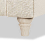 A wooden furniture leg supports an upholstered piece, against a plain background.