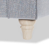 A wooden furniture leg supports a section of blue upholstered furniture against a white background.