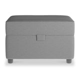 A gray upholstered storage ottoman with a lid and short legs stands isolated against a white background.