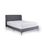 A gray upholstered bed with a quilted white mattress, set against a white background, suggesting a clean, minimalist setup.