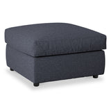 A square, navy blue upholstered ottoman with short black legs, positioned against a white background.