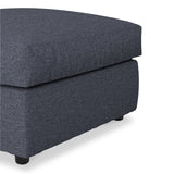 A dark grey ottoman on a white background, featuring a fabric texture and visible black feet.