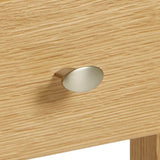 A metal drawer knob affixed to a wooden surface, suggesting a piece of furniture, possibly a cabinet or dresser.