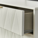 A white cabinet drawer with a textured front is partially open, revealing a grey interior liner and hints of stored items. It's set against a white backdrop.