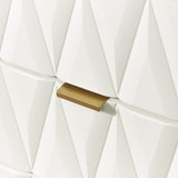 A gold door handle is affixed to a textured white wall with a geometric pattern.